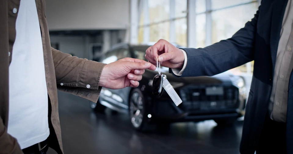 La main masculine donne une clé de voiture à la main masculine en gros plan dans le concessionnaire de voitures