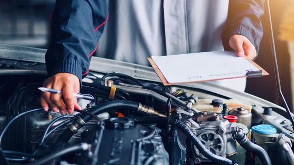 Atelier de réparation automobile avec véhicule blanc, capot ouvert révélant le compartiment moteur