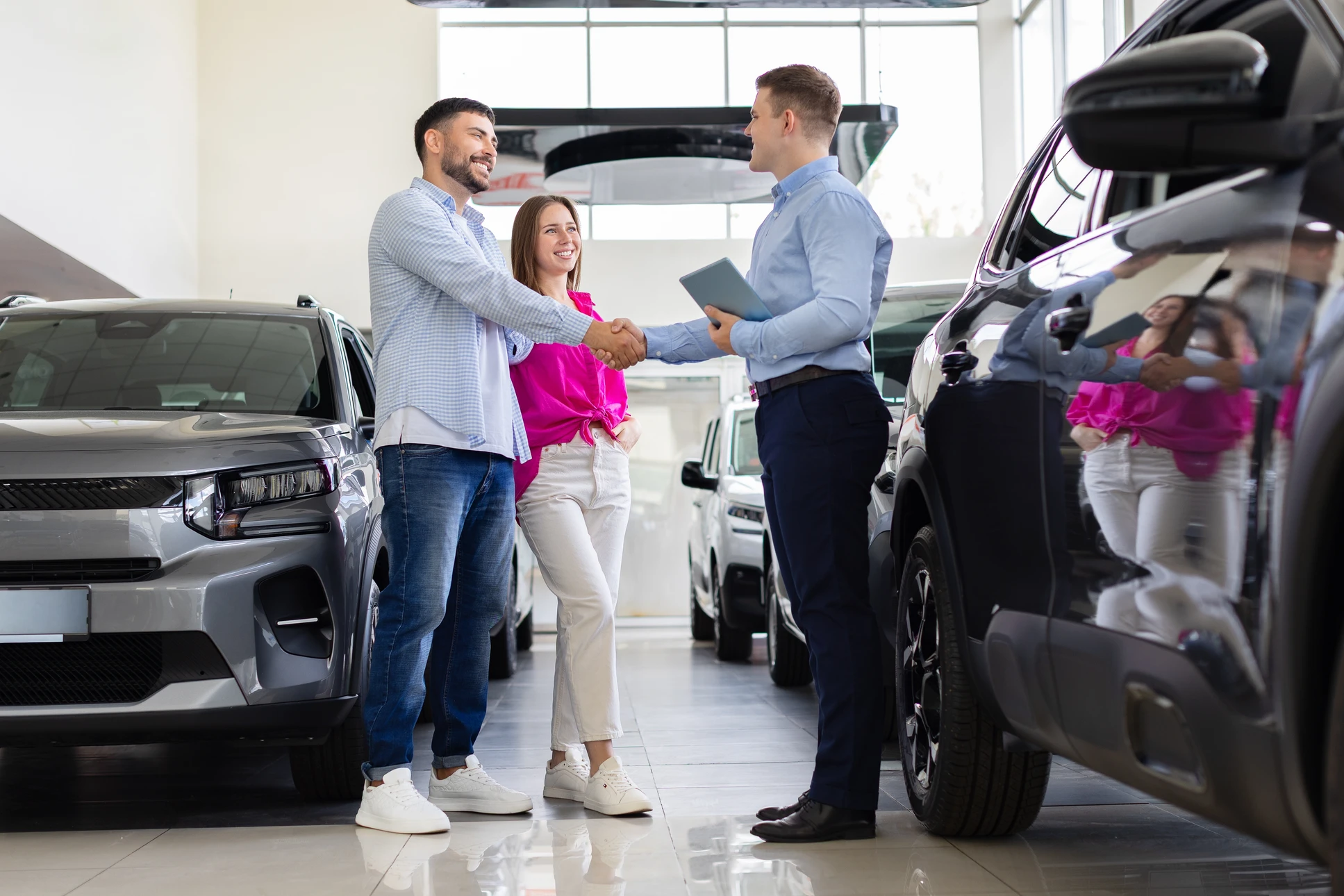 Parking extérieur ensoleillé montrant une sélection de véhicules d'occasion de marques et modèles variés (berlines, SUV, citadines, breaks) bien entretenus, alignés en rangées organisées. Les véhicules présentent des signes d'usage normal et une bonne condition générale, reflétant la qualité des occasions proposées. L'atmosphère doit être professionnelle, organisée et rassurant, avec une bonne luminosité naturelle mettant en valeur l'état des véhicules.